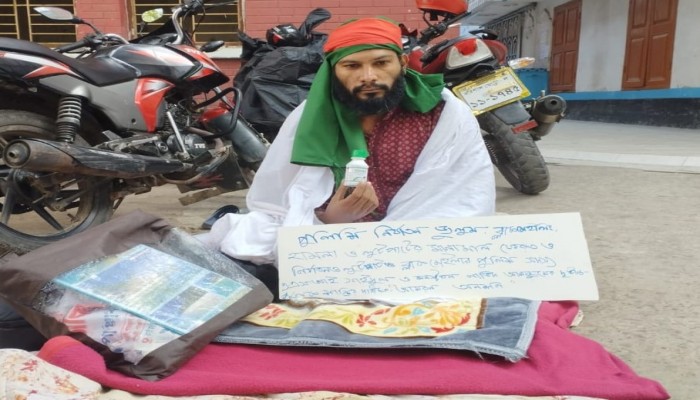 শরীরে কাফনের কাপড় জড়িয়ে বিষের বোতল নিয়ে সাংবাদিকের অবস্থান